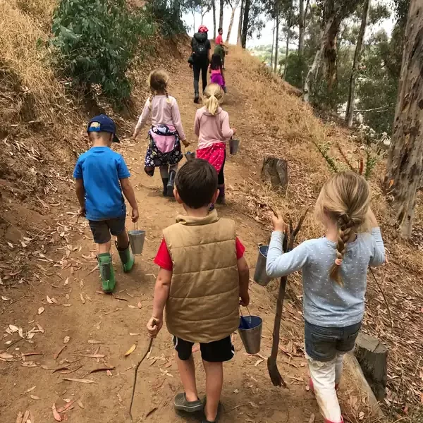Children participating in a homeschool enrichment program hike a wooded trail during a nature-based learning day at Nature Scouts Collective