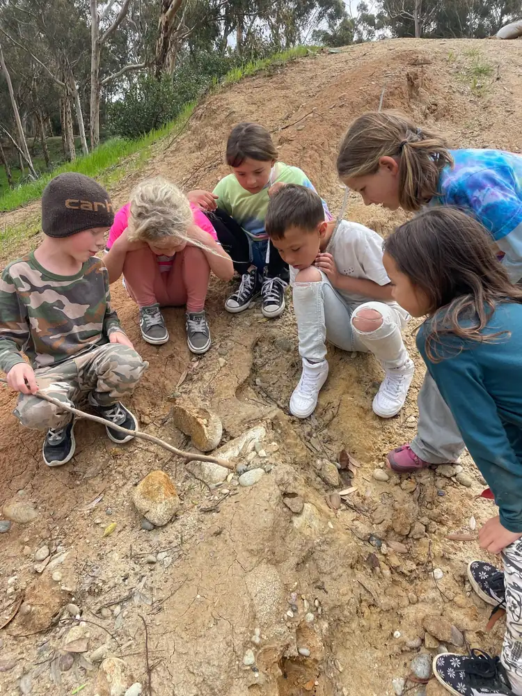 Junior Scouts children exploring rocks, soil, and natural materials during an outdoor nature-based learning activity in North County San Diego.