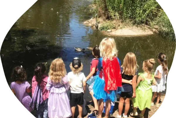 Children gather outdoors by a pond during a Nature Scouts Collective nature-based learning activity.